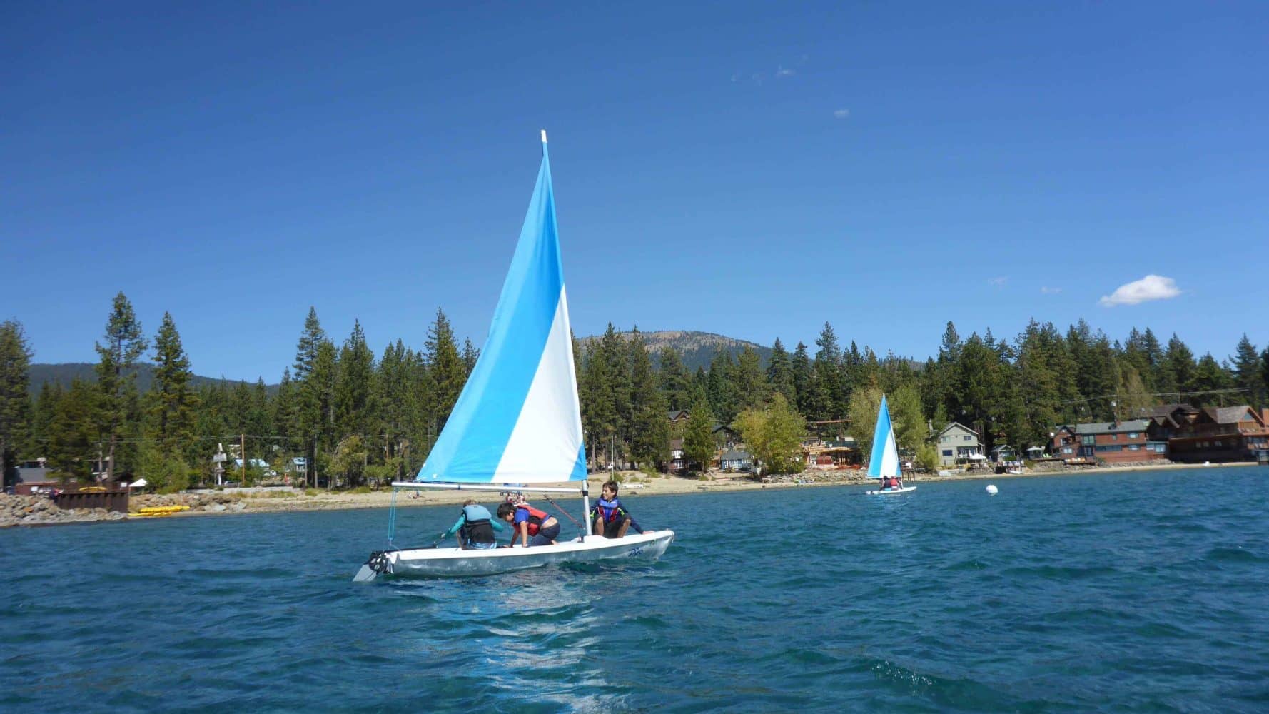 students in the ocean on small sailboats