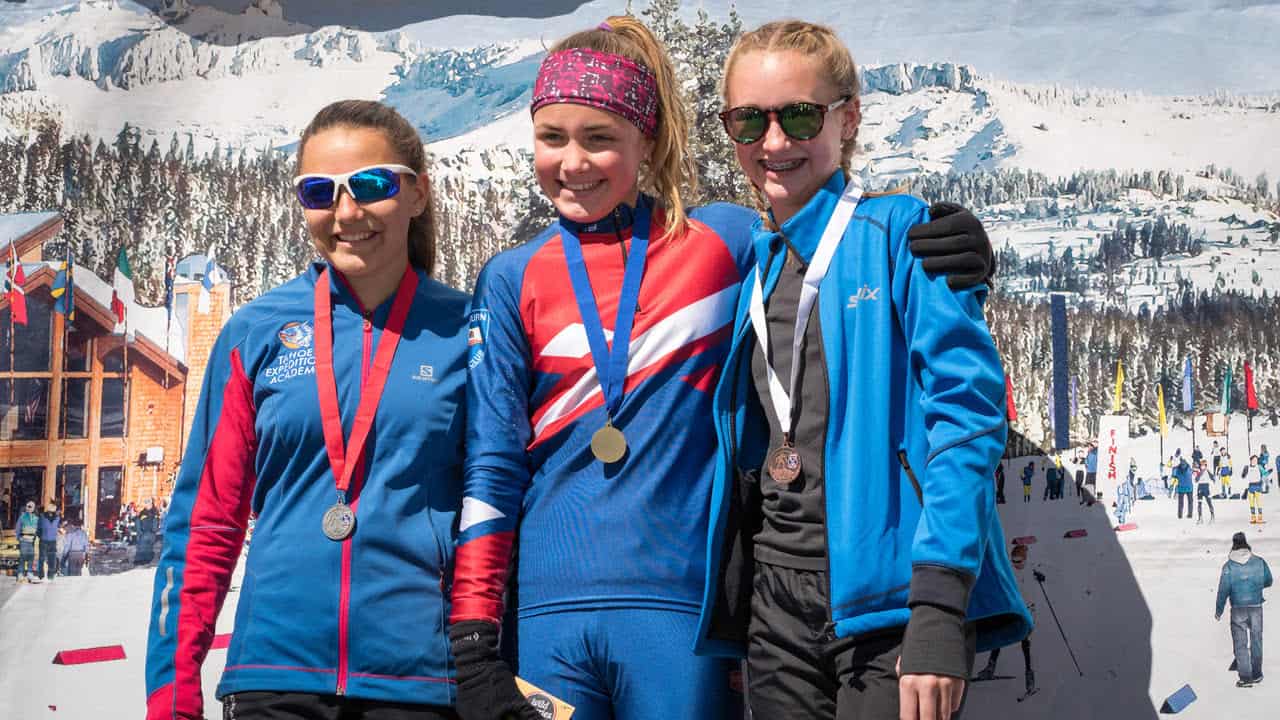 biathletes with medals atop the podium