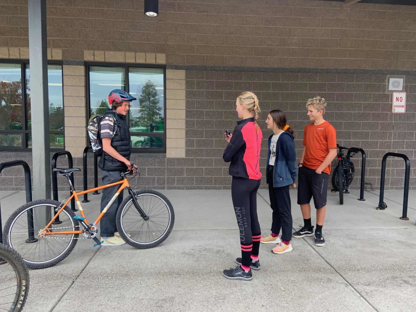 students talk with their peer riding his bike