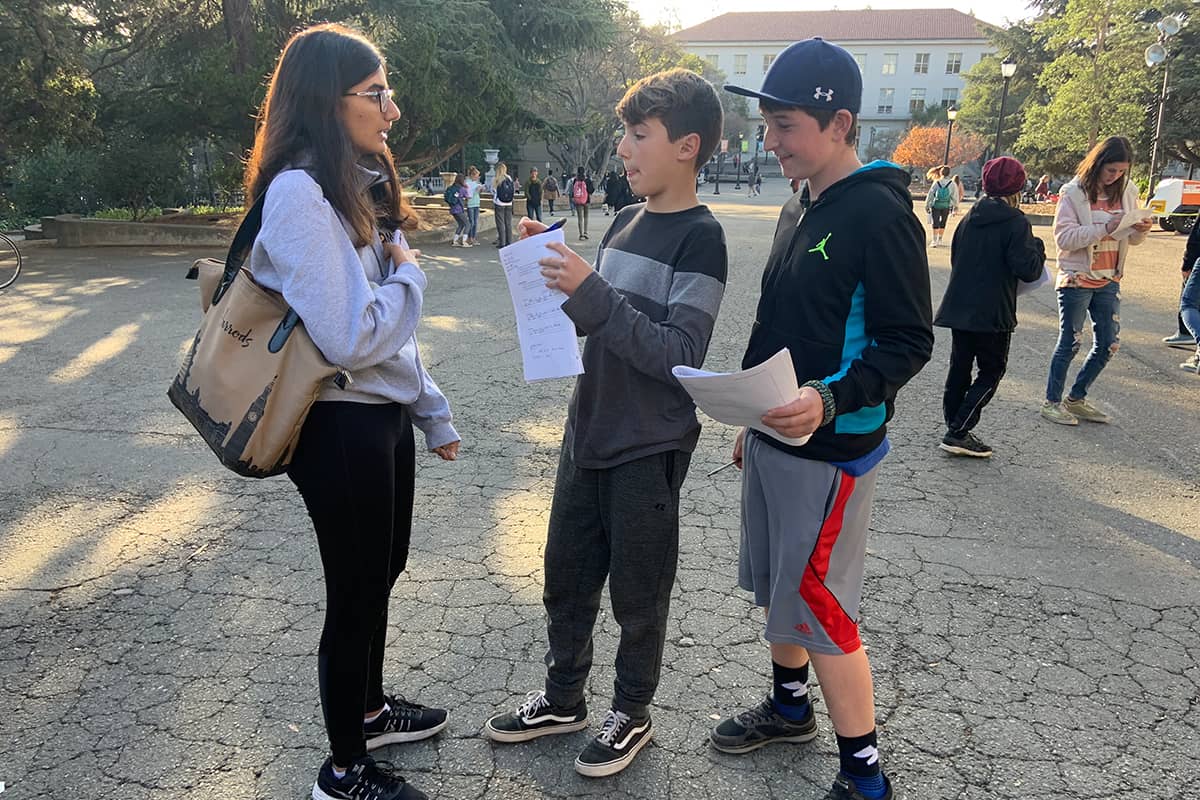 two students talking outside with a teacher